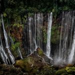 Stunning view of Tumpak Sewu Waterfall cascading in a lush jungle setting in East Java, Indonesia.