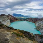 A breathtaking view of the turquoise Ijen Crater Lake surrounded by rugged mountains in Indonesia.