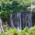 Tumpak Sewu Waterfall cascading through green forest in East Java, Indonesia.