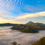 A breathtaking view of Mount Bromo in East Java, Indonesia, surrounded by misty clouds at sunrise.